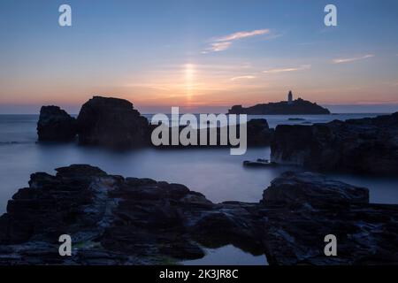 Langzeitaufnahme des verwackelten Leuchtturms cornwall bei Sonnenuntergang mit verschwommener Bewegung im Wasser Stockfoto