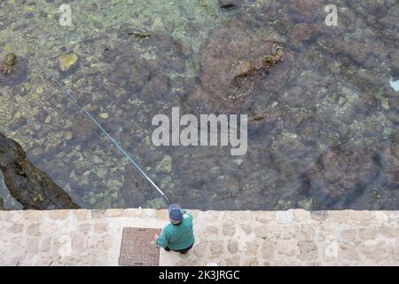 Von den Verteidigungsmauern der Altstadt von Dubrovnik aus gesehen, Blick nach unten auf einen Sportfischer. Dalmatien, Kroatien, Europa. Stockfoto