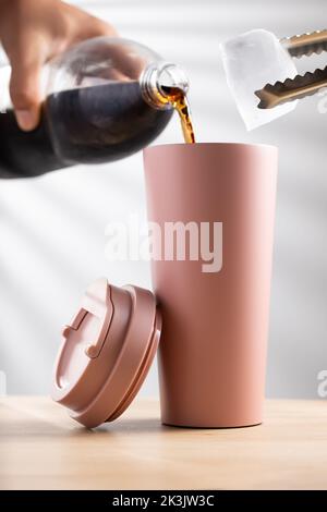 Setzen Softdrink und Eiswürfel in einem pastellrosa Becher Größe 20 Unzen Stockfoto