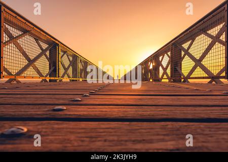 Landschaftlich schöne Aussicht auf die Brücke, die zum gelben Licht bei Sonnenuntergang in Biarritz, Frankreich, führt Stockfoto