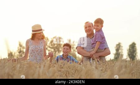 Glückliche Familie genießt es, Sommerferien auf Weizenfeld zu verbringen Stockfoto