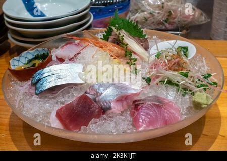 Große Eisschale aus Glas mit verschiedenen Sashimi-Stücken. Traditionelles Sashimi-Gericht im japanischen Fischrestaurant in Tokio. Stockfoto
