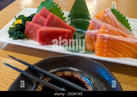 Scheiben von frischem rohem Thunfisch und Lachs auf einem weißen Teller. Traditionelles Sashimi-Gericht im japanischen Fischrestaurant in Tokio. Stockfoto