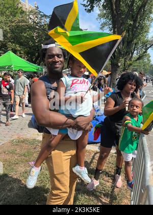 Portrasi von jamaikanischem Vater und Tochter mit Flagge in der Hand bei der West Indian Day Parade am Labor Day in Brooklyn, New York. Stockfoto