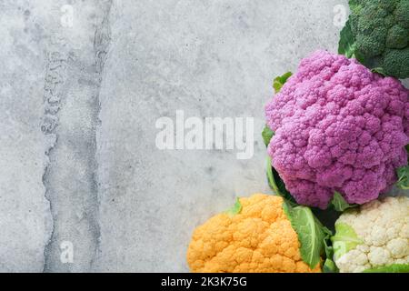 Colorfu-Blumenkohl. Verschiedene Arten von Blumenkohl auf grauem Beton Hintergrund. Violette, gelbe, weiße und grüne Farbkabbage. Brokkoli und Romanesco. Stockfoto