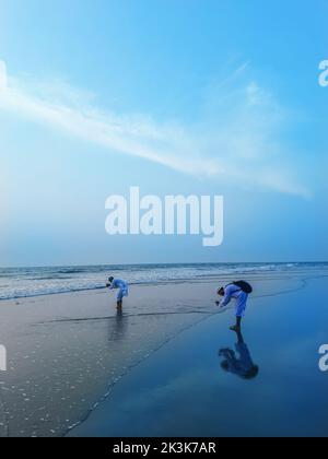 Mann, der mit dem Handy am tropischen Strand fotografiert. Junger Mann, der mit seinem Smartphone ein Bild vom Meer machte. Stockfoto