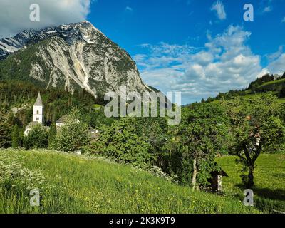 Eine schöne Aufnahme der Pfarrkirche im kleinen Dorf Purgg und Grimming Peak in der Steiermark, Österreich Stockfoto