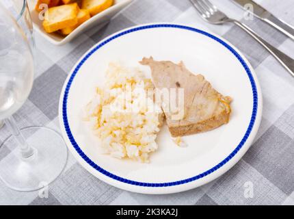 Gegrillte Thunfisch-Steaks mit weißem Reis, serviert auf einem Teller mit Besteck und Brot Stockfoto