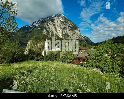 Die Pfarrkirche und Häuser im Dorf Purgg mit dem Grimming-Gipfel im Hintergrund, Steiermark, Österreich Stockfoto