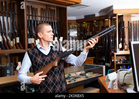 Porträt eines Verkäufers in einem Waffenladen mit einer Kugelpistole in den Händen Stockfoto