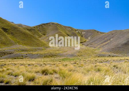 Lindis Pass, eine bergige Straße (Highway 8) durch eine karge Landschaft aus tussockigen Wiesen im Lindis Pass Scenic Reserve in der Ökoregion von Sout Stockfoto