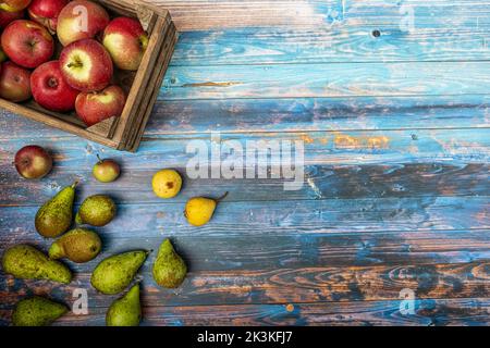 Blick von oben auf eine alte Holzkiste voller knackiger Äpfel und Birnen Stockfoto