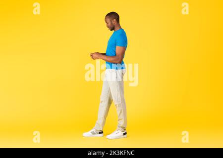 Volle Länge Von Schwarz Männlich Mit Smartphone Über Gelben Hintergrund Stockfoto
