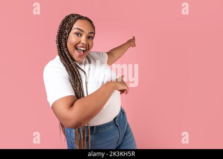 Aufgeregt Afroamerikanische Frau Zeigt Die Finger Beiseite Über Rosa Hintergrund Stockfoto