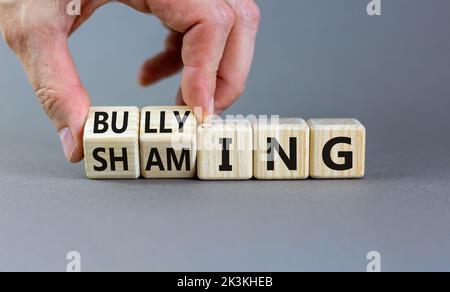 Symbol für Scham und Mobbing. Konzeptworte Shaming and Mobbing auf Holzwürfeln. Geschäftsmann Hand. Schöne graue Tabelle grauen Hintergrund. Geschäftsvorgetäuscht Stockfoto