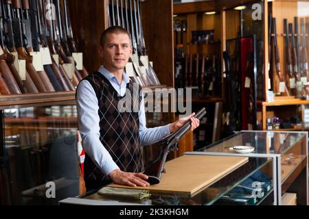 Der Besitzer des Waffenladens zeigt ein seltenes Sammlergewehr Stockfoto