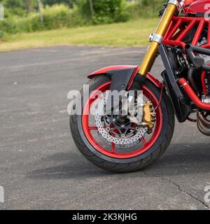 Die Nahaufnahme eines roten Motorrad-Vorderrads auf dem Asphalt Stockfoto