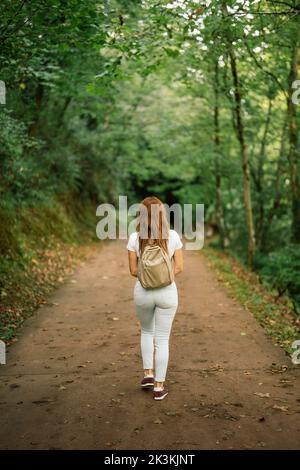 Frau, die auf einem unbefestigten Weg mitten in einem Wald geht Stockfoto