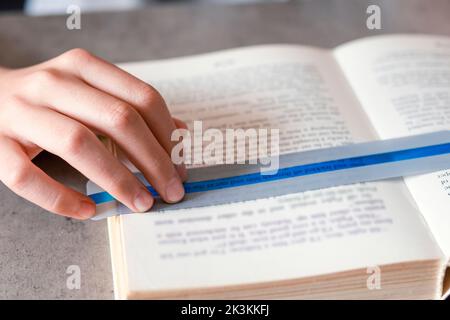 Lesetools für Legasthenie. Kinder lesen Buch mit bunten Lineal Overlay Streifen. Bildung, Lernbehinderung, Leseschwierigkeiten Konzept Stockfoto