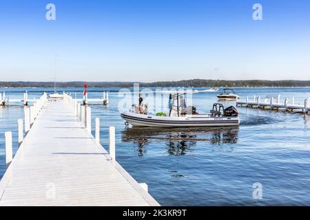 Kleines Schlauchboot, das an einem weißen Holzpier in der Nähe von Fontana, Lake Geneva, Wisconsin, Amerika, ankommt. Stockfoto