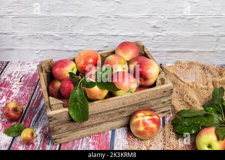 Dekorative Holzkiste mit frischen Äpfeln auf einem alten Tisch Stockfoto