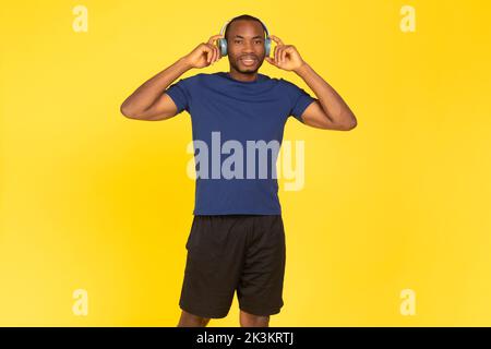 Athletic African American Man Trägt Kopfhörer Musik Hören, Gelber Hintergrund Stockfoto