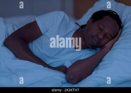 Porträt eines jungen afroamerikanischen Mannes, der in der Nacht im Bett schläft Stockfoto