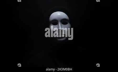 Mann trägt Maske mit Hoodie auf schwarzem Hintergrund. Stockfoto