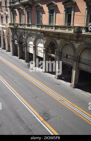 Porticoes entlang der Via dell'Indipendenza mit einsamen Radfahrern und ohne Autos in Bologna Emilia Romagna Italien Stockfoto