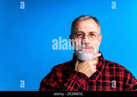 Alter gut aussehender Mann, der wichtige Lebensentscheidungen trifft blaues Backgrond-Studio Stockfoto