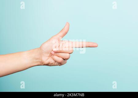 Frau zeigt mit der Hand. Weibliche Hand zeigt den Finger auf etwas auf hellblauem Hintergrund. Vorderansicht Stockfoto