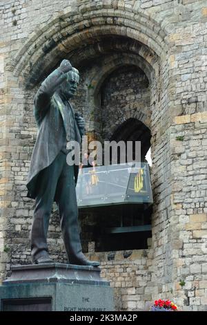 Statue von David Lloyd George, ehemaliger Premierminister von Großbritannien, mit dem Queen's Gate of Caernarfon Castle im Hintergrund. Stockfoto