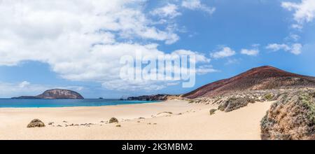 Malerischer Panoramablick auf türkisfarbenes Meerwasser, das am Sandstrand gegen den wolkigen blauen Himmel in Playa de las Conchas auf Lanzarote, Spanien, rollt Stockfoto