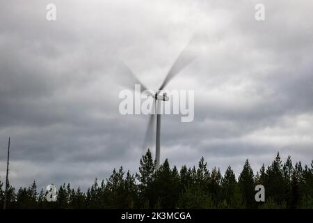 Drehende Windkraftanlage gegen den bewölkten Himmel, Langzeitbelichtung in Otanmäki, Finnland Stockfoto