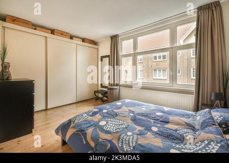 Breites bequemes Bett mit warmen Decken im trendigen Schlafzimmer der modernen Wohnung mit Kleiderschrank Stockfoto