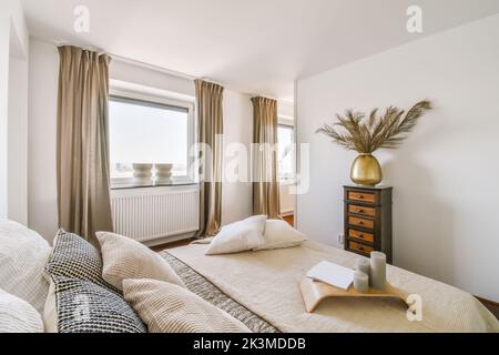 Breites, komfortables Bett mit warmen Decken und weichen Kissen im trendigen Schlafzimmer des modernen Apartments Stockfoto