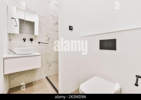 Modernes Badezimmer mit Waschbecken und Toilette an den Wänden mit Marmorfliesen im modernen Badezimmer Stockfoto