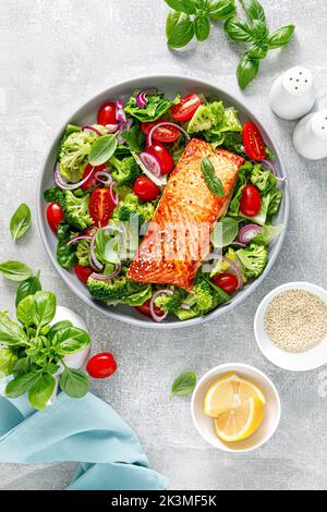 Gegrilltes Lachsfischfilet und frischer grüner Gemüsesalat mit Tomaten, roten Zwiebeln und Brokkoli. Gesunde Ernährung. Ketogenes Mittagessen. Draufsicht Stockfoto