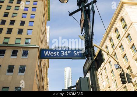 Wunderschöner Blick auf die Stadt und die Dächer der Gebäude auf dem Hintergrund des blauen Himmels. Schild der West 34. Street. New York. USA. Stockfoto