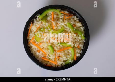 Schezwan Chicken Fried Rice in weißer Schüssel isoliert auf weißem Hintergrund. Szechuan Rice ist ein indochinesisches Gericht mit Paprika, grünen Bohnen und Auto Stockfoto