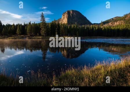 Haynes Peak Reflection im Madison River, Yellowstone National Park. Das Sonnenlicht am frühen Morgen erzeugt weiche und warme Herbstfarben. Stockfoto