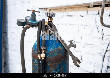 Alte Gasflaschen zum Schweißen und Schneiden. Rostige Propan- und Sauerstofftanks. Werkzeuge für die metallverarbeitende Industrie. Verlassene Baustelle. Stockfoto