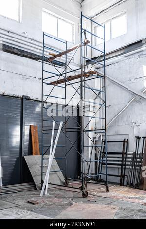 Bau einer Arbeitswerkstatt im Werk. Reparatur des Arbeitsraums. Gerüste, Leitern und Arbeitswerkzeuge. Stockfoto