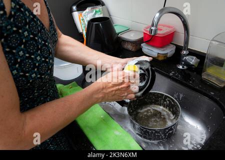 Junge Frau, die Pfanne und Utensilien in der Küche waschen. Hygiene in der Küche. Salvador, Bahia, Brasilien Stockfoto