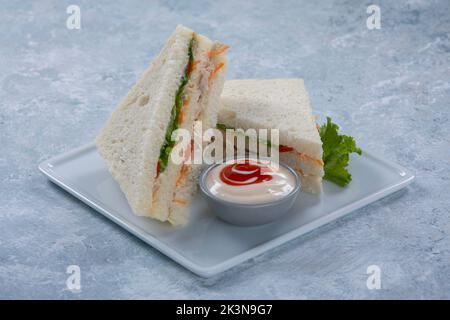 Sandwiches mit Schinken, Käse, Speck, Tomaten, Salat, Gurken und Zwiebeln auf dunklem Holzhintergrund Stockfoto