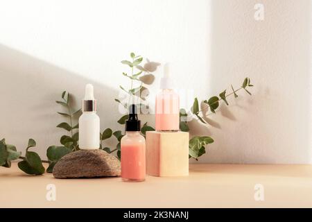 Kosmetische Tropfflaschen und Eukalyptuszweig im Sonnenlicht. Naturkosmetik und Aromatherapie Konzept. Stockfoto