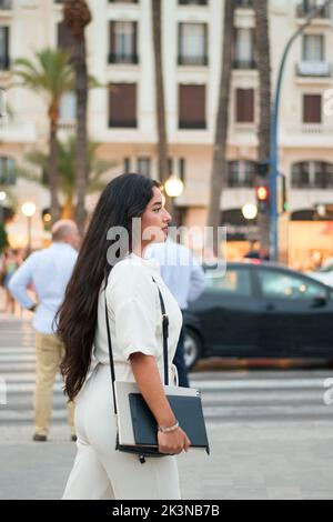Latina Geschäftsfrau mit Notebook und Tablet geht auf die Straße Stockfoto