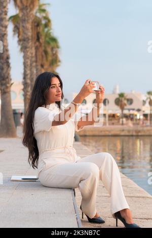 Latina Geschäftsfrau macht ein Foto mit ihrem Telefon in einem Hafen Stockfoto