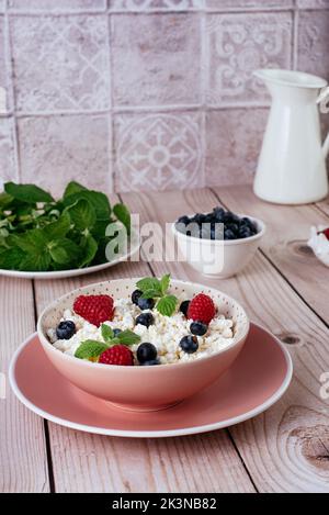 Quark in einer Schüssel mit frischen Beeren auf einem Holztisch Stockfoto