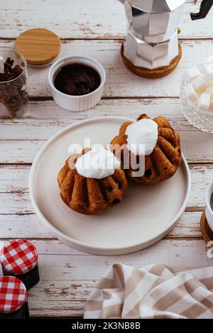 Cupcakes mit Buttercreme, Kaffee auf hellem Holzhintergrund Stockfoto